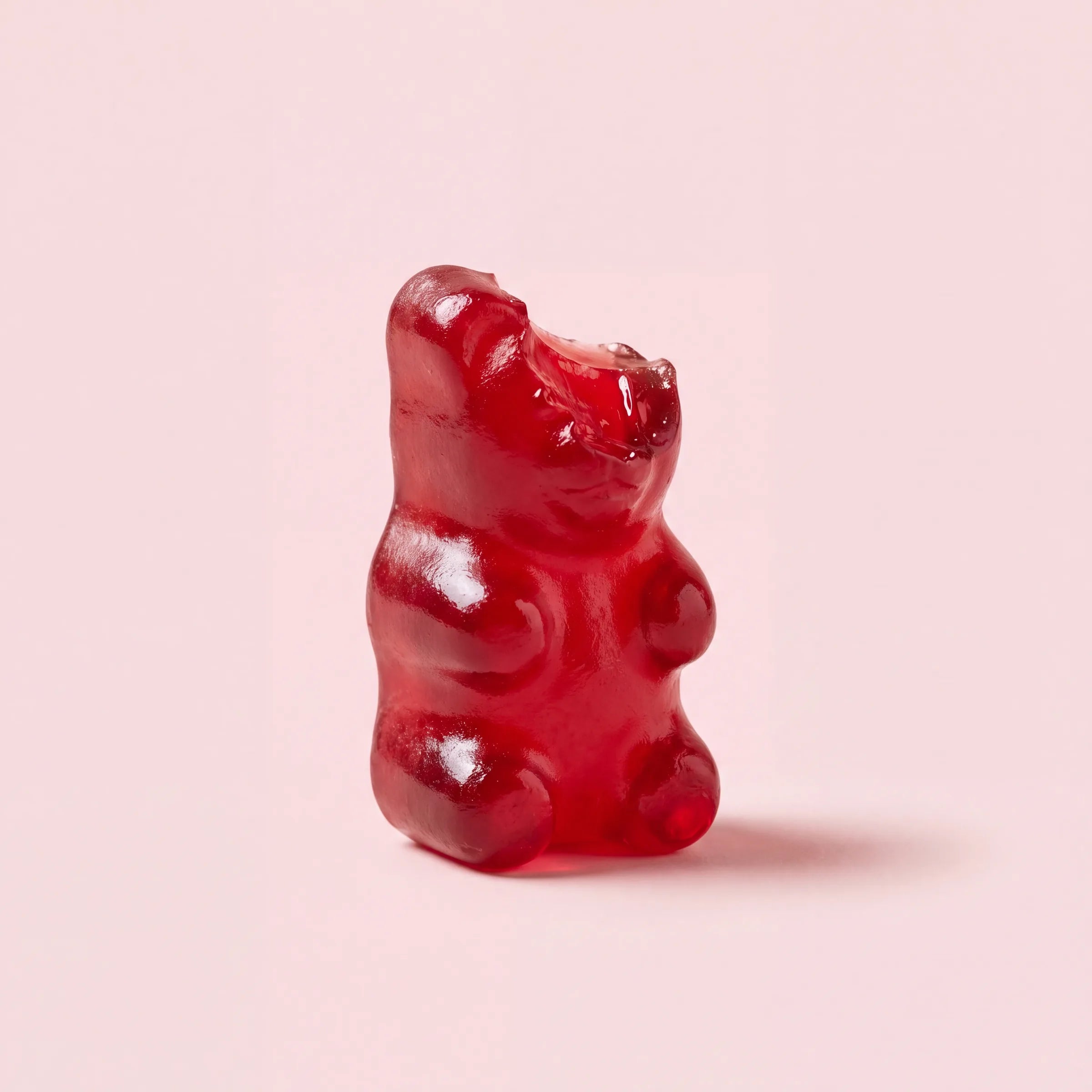 Rode gummy met een hapje eruit op zacht roze achtergrond